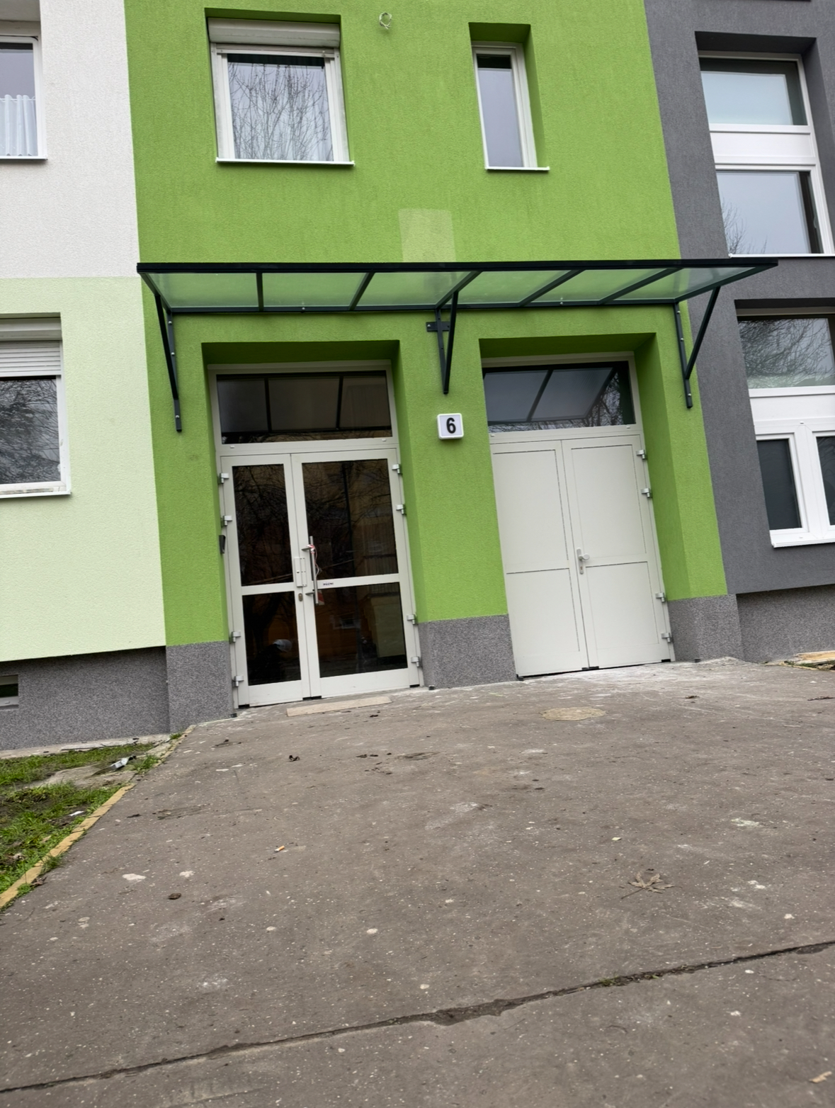 Egyedi gyártású előtető szerkezet készült statikailag méretezett acélvázzal, az épület adottságaihoz igazítva. A fedést drótüveg biztosítja, amely tartós, időjárásálló megoldást nyújt, miközben megőrzi a bejárat világosságát.